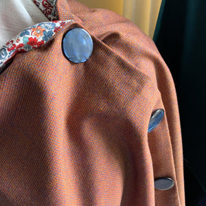 Rust coloured wool fabric wrap with large blue buttons and floral print cotton lining